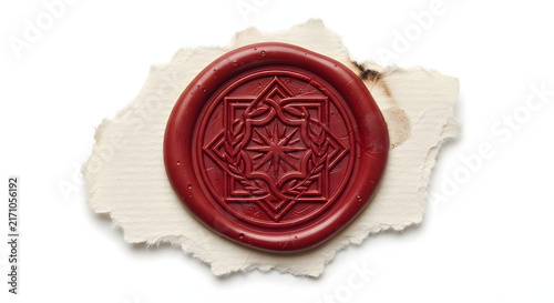 Red wax seal stamp with intricate geometric star emblem on torn parchment paper.
