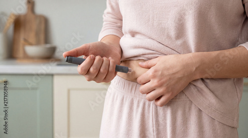 Woman pinching abdomen skin before an insulin pen injection to manage diabetic blood sugar levels at home. Concept of diabetes, chronic illness, glucose monitoring, hyperglycemia, and hypoglycemia.