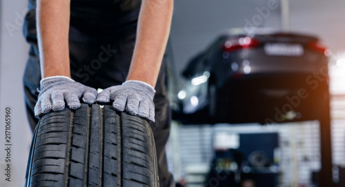 Car wheel service: mechanic in blue overalls working on tire replacement in garage.