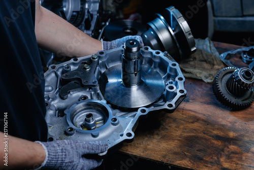 Worker inspecting gearbox housing on wooden workbench in repair shop, fix service concept