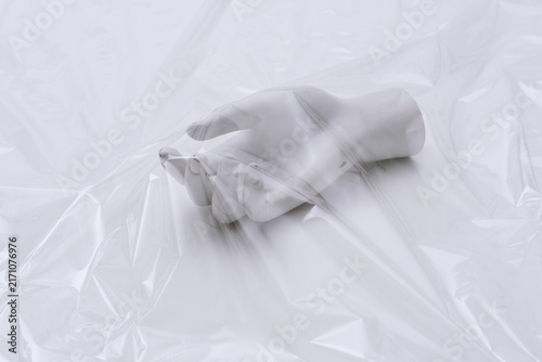 Foto Mannequin Hand Reaching Under Plastic Foil Symbolizing Environmental Crisis