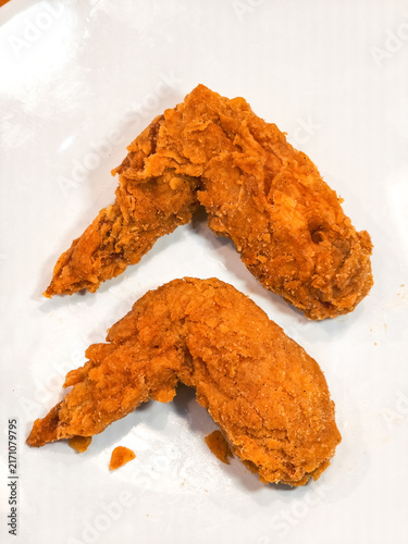 Golden Crispy Fried Chicken Wings on White Plate. Two golden, deeply crispy battered whole fried chicken wings rest on a plain bright white plate.