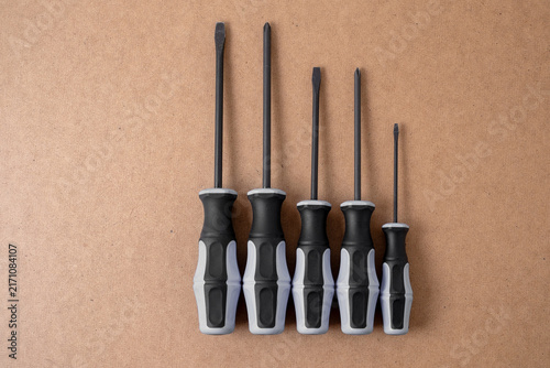 Fotografie Five screwdrivers standing upright on hardboard background, top view