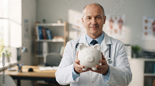 Male doctor holding a piggy bank, symbolizing financial planning for healthcare, representing savings and investment in well-being.