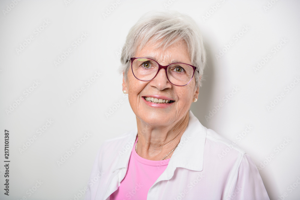 Fototapeta premium Portrait of elderly woman with eyeglasses over studio white