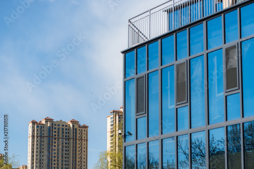 Modern glass‑curtain‑wall building and distant high‑rise residential buildings