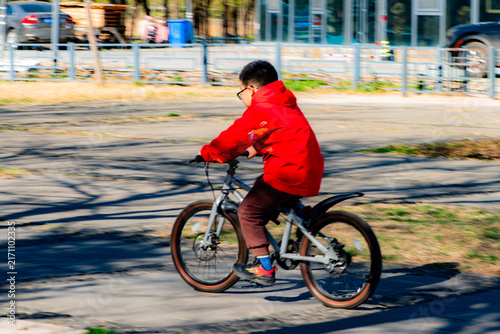 Boy in red jacket riding mountain‑bike outdoors