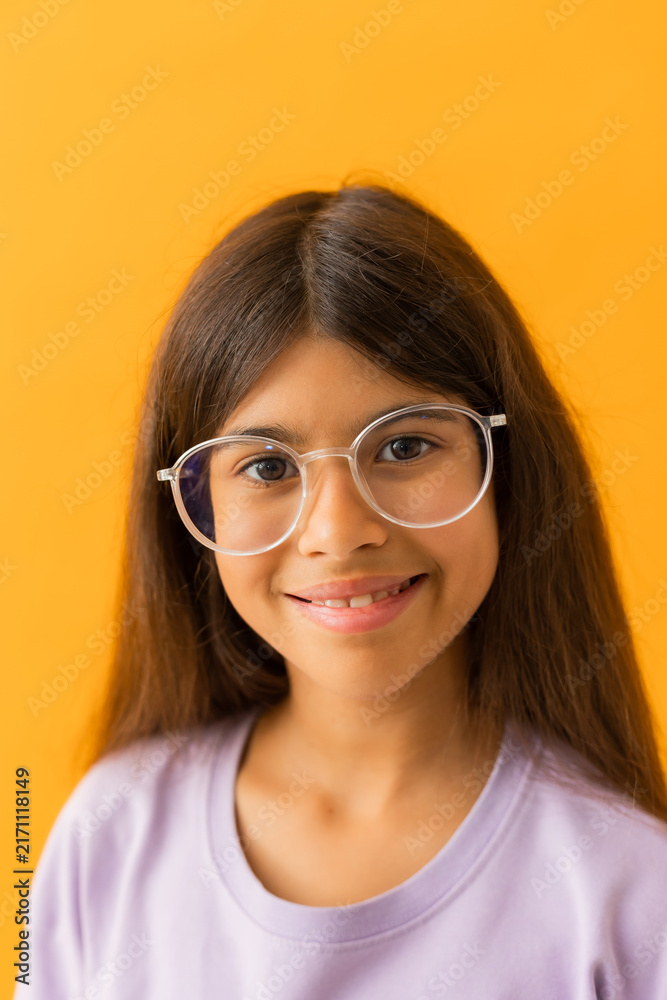 Obraz premium little brunette girl in glasses for vision against a yellow background