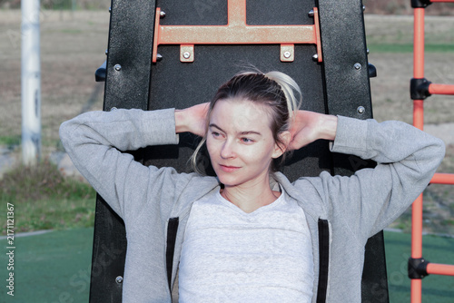 Foto Blonde woman doing crunches on inclined sit-up bench at outdoor gym