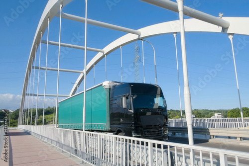 Articulated Lorry Transporting Cargo Across Modern Arch Bridge.