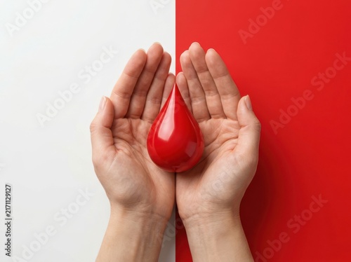 Hands cradling red blood drop symbol, representing donation life saving blood bank and medical health