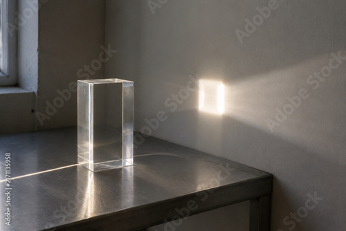 Sunbeam passing through clear acrylic block onto white wall, light transmittance concept