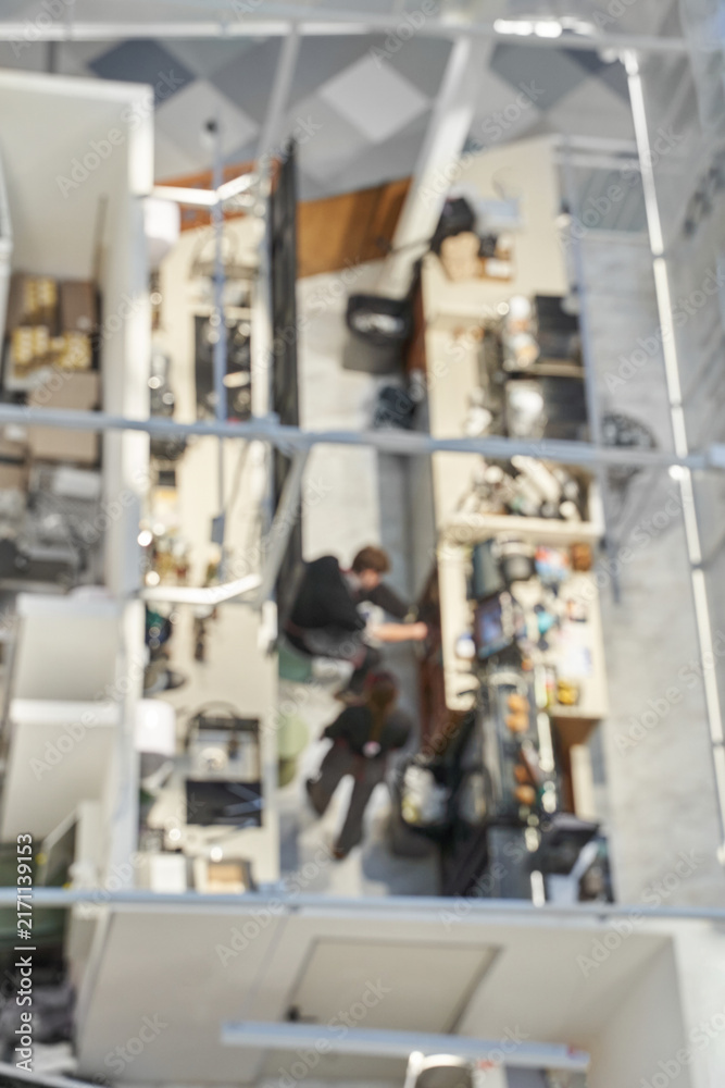 Fototapeta premium Office Cubicles Occupied Employees Working At Desks Inside Open Plan Corporate Workspace Viewed From High Angle With Blurred Focus On Activity.
