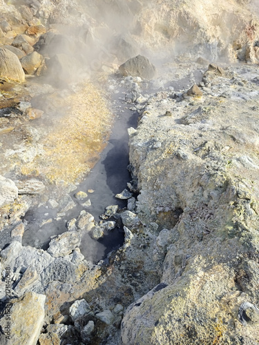 Foto Close view of a steaming fumarole surrounded by yellow sulphur deposits and altered rock in a geothermal field in Iceland