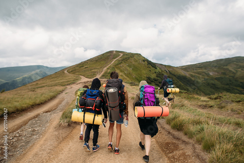 young people with backpacks hiking in the magical mountains