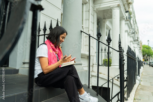 Canvas Print Woman writing in a journal on steps in front of Georgian houses in London, enjoy