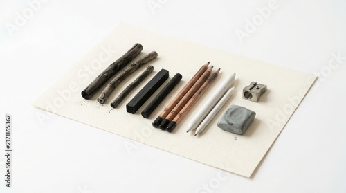 Set of drawing charcoal sticks pencils erasers arranged on a white paper sheet artist erasers sketching tools art supplies drawing materials charcoal sketching supplies materials