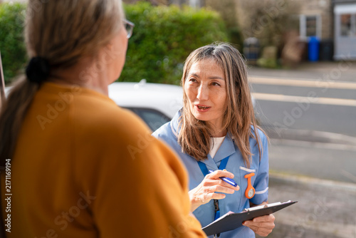 Health worker talks to a person at their home during a community health visit in the neighborhood