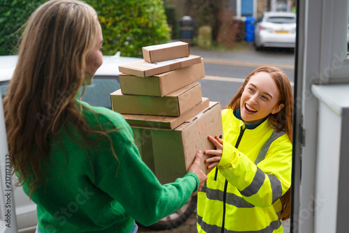 Foto Delivery person hands over several packages at a home entrance in a residential