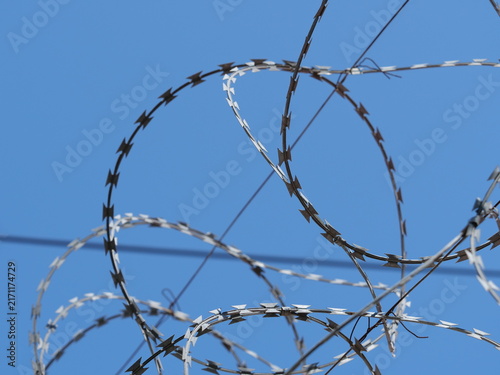 Fotografie Razor wire border fence symbolizing refugee crisis and migration