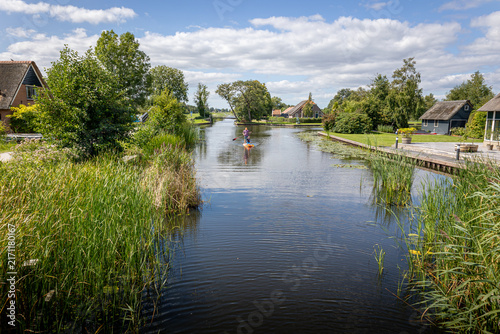 Peaceful scene in the national park called the 'weerribben' with a person paddleboarding.