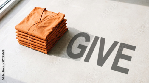 A neat stack of folded orange vests placed on a flat surface with the word give with rests light surface give cast shadow philanthropy humanitarian organization with contribution