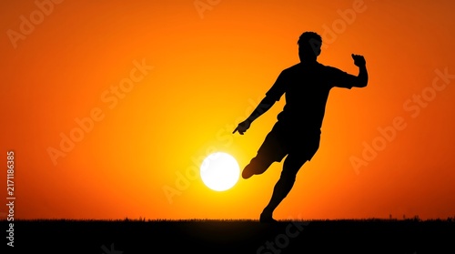 Silhouette of a male athlete running outdoors against a bright orange sunset background with dark figure runner moves across field during vibrant sunset