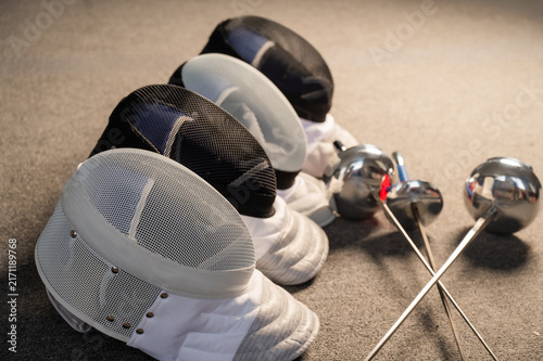 Canvastavla Fencing equipment. Swords and masks on the gray floor.