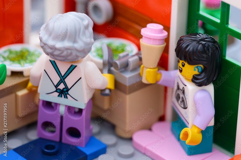 Fototapeta premium Tambov, Russian Federation - January 27, 2026 A close-up shot of a Lego girl minifigure holding an ice cream cone while visiting a grandmother in a kitchen.