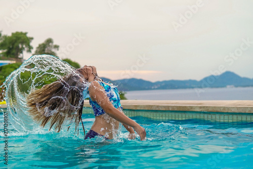 Obraz na płótnie niña rubia en alberca frente al mar en la playa con su cabello volando mojado di