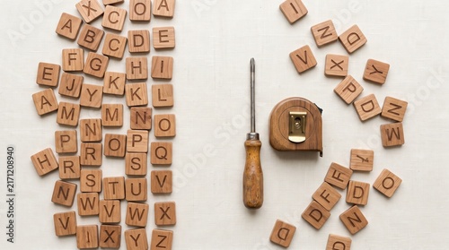 Wooden alphabet tiles scattered with screwdriver and measuring tape