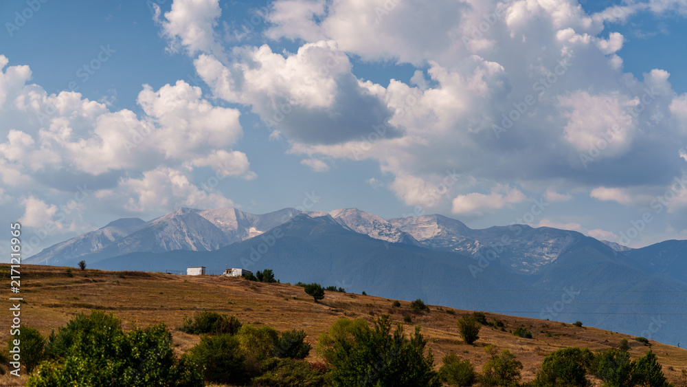Obraz premium Rural fields and mountains under cloudy sky