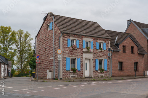 Принти на полотні Traditional brick house with blue shutters stands on a quiet street in Zons, Ger