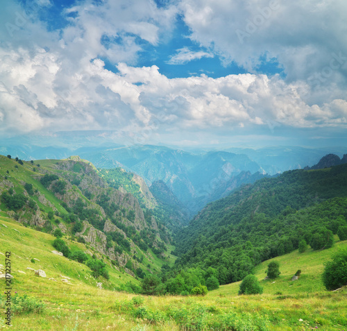 Quadro su tela Deep green mountain canyon stretches below majestic white clouds and blue sky in Balkan park