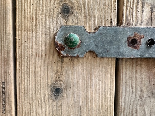 Fotografie A close-up of an old, rusty metal door trim on a wooden door.