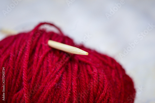 Canvas Print Ball of deep red yarn with wooden circular knitting needles inserted into it close-up