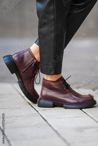 Obraz na plátně person wearing burgundy boots standing on urban sidewalk close-up of feet casual street style fashion commercial natural light clean background copy space editorial educational visual story