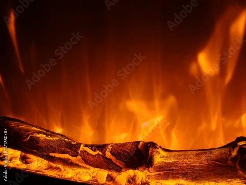 Glowing artificial log surrounded by flames in an electric fireplace