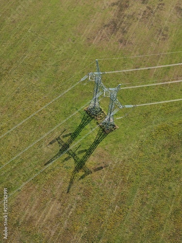 Cuadro en lienzo Electricity pylon casting a long shadow across a green field