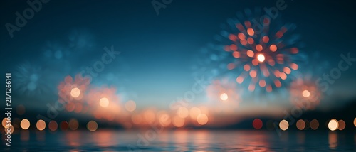Night sky lit by colorful fireworks reflected in calm water