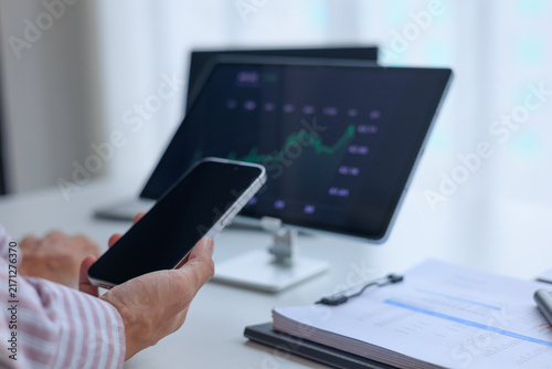 Businessman reviews a green upward chart of stock market trend on tablet at his office desk.