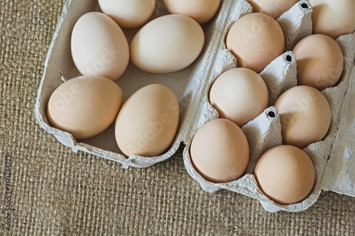 Brown Chicken Eggs in Cardboard Cartons on Burlap Background, Top View