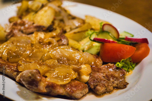 Traditionelles Thüringer Rostbrätl mit geschmorten Zwiebeln, Bratkartoffeln und frischem Salat auf einem Teller, Ziegenrück, Thüringen, Deutschland