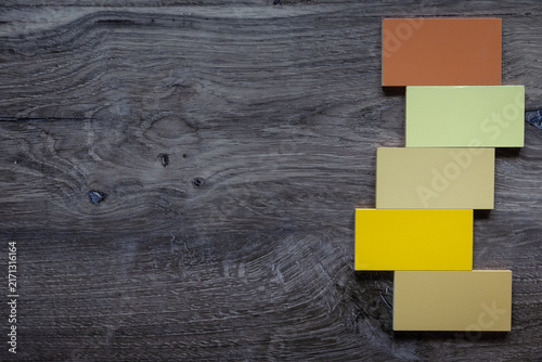 Birds eye view photo of dark wood background with negative space and yellow brown five tiles to the right. 