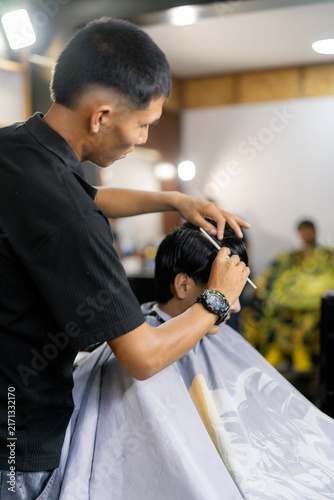 Barber styling man's hair in modern barbershop