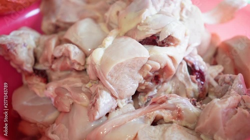 Fresh raw chicken pieces piled in a pink plastic bowl ready for cooking. Close-up shot highlights texture and natural color of unprocessed poultry meat, elegantly showcasing preparation.