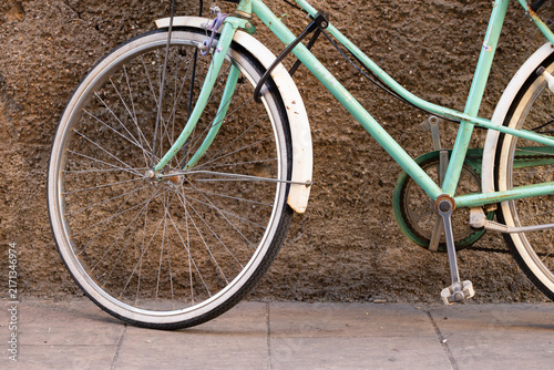 Fotografie Vintage bicycle with a turquoise frame and white tires leaning against a texture