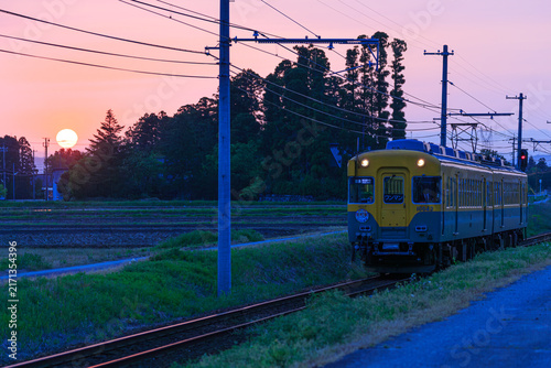 Fotografía 日没間近の太陽が輝かせる線路を富山地方鉄道の愛称「かぼちゃ電車」が走る