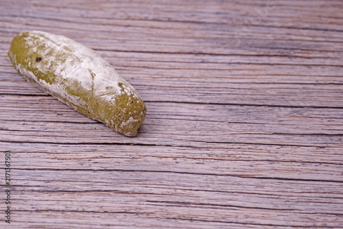 Fresh sourdough dusted lightly with flour rests on wooden surface. Subtle cracks mark its golden crust. Soft lighting enhances texture and warmth. Simplistic background draws focus to baked good