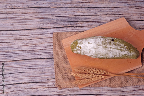 Fresh sourdough dusted with flour rests on wooden board. Golden wheat stalks lie beside it, adding rustic charm. Burlap cloth and warm tones create cozy kitchen ambiance. Perfect for food blogs